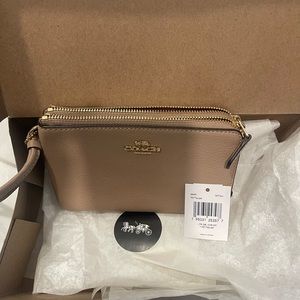 Coach wristlet, tan with double zipper. Never used.Box and coach tissue paper.